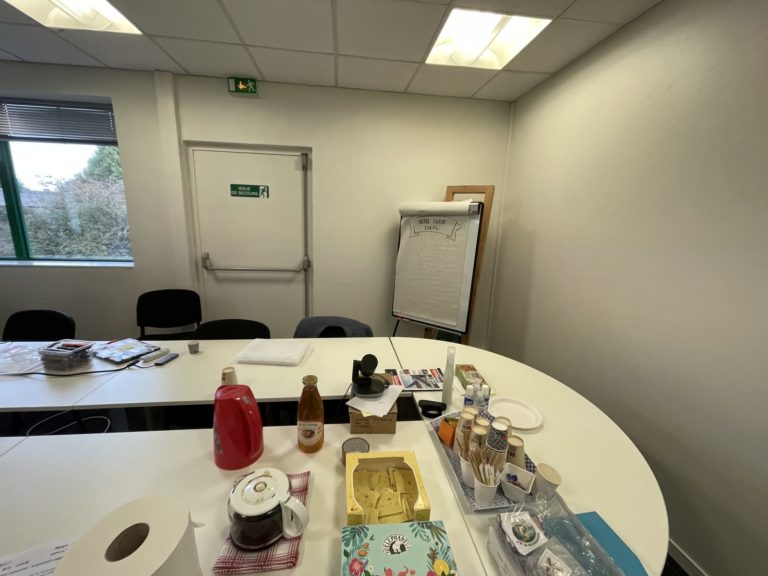 Salle prête avant l'arrivée du groupe : tables en U, café, paperboard, sans personne