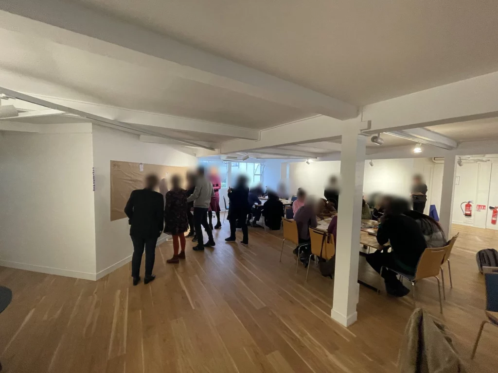Déroulé pédagogique : un groupe debout devant un mur de kraft, une autre partie travaille aux tables